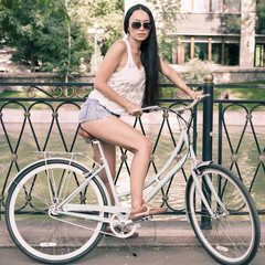 asian woman riding by blue vintage city bicycle at the city center. It is like concept for activity and healthy lifestyle and environmentally friendly transport