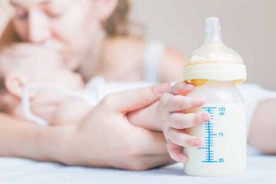 Baby holding a baby bottle with breast milk for breastfeeding. Mothers breast milk is the most healthy food for newborn baby.