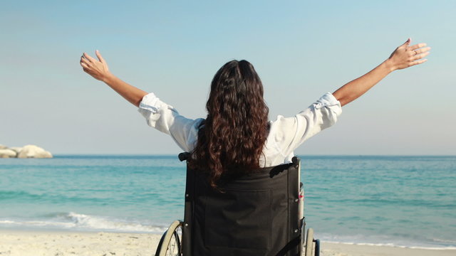 Disabled woman with arms outstretched at the beach