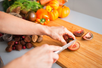 Closeup of woman's hands holding and slicing tomato