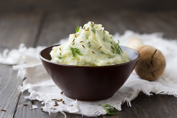 Mashed potatoes with yogurt, tehina, cilantro and spices in a ceramic bowl on a wooden table