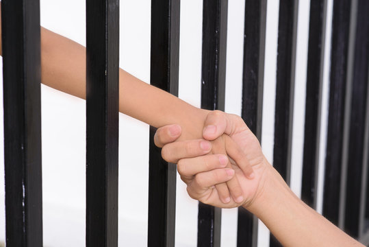 Man hand hold kid hand from the jail