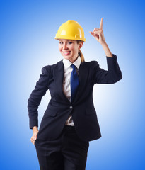 Young businesswoman with hard hat against gradient 