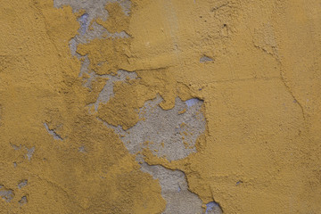 Texture of old rustic wall covered with yellow stucco