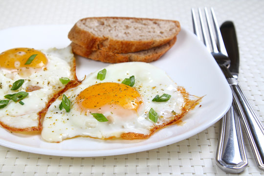 Fried eggs on the white plate, shallow focus