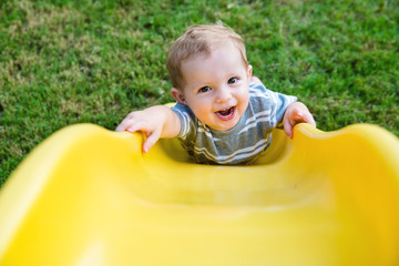 Young toddler boy child playing on slide at playground outdoors