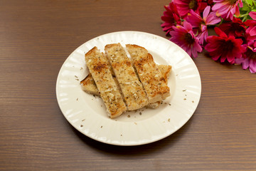 Garlic bread on white plate and flower on wood background