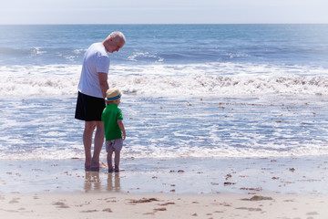 grandfather with his grandson walking on a beach