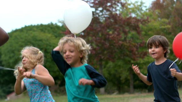 Happy children playing with balloons at the park