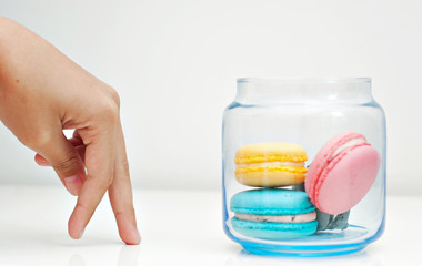 Hand moving towards a jar of macaroons