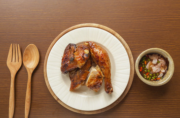 Thai style grill chicken with spicy sauce with space on wood background