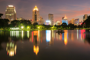 Obraz premium Pejzaż dzielnicy biznesowej z parku z czasem zmierzchu z Lumpini Park, Bangkok, Tajlandia