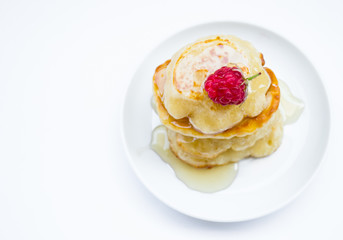 Stack of pancakes on plate, raspberries and honey, top view
