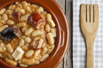 Spanish fabada in an earthenware dish and a wooden fork