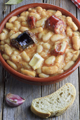 Spanish fabada in an earthenware dish with bread and garlick