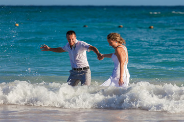 Young wedding couple have a fun in ocean waves