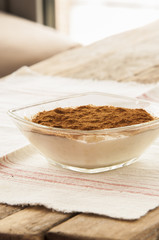 Rice pudding sprinkled with cinnamon powder in an individual glass bowl.