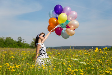 Junge Frau im Retro Look und vielen bunten Luftballons auf einer