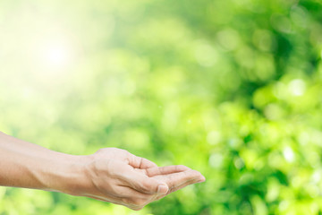 Hands over  abstract green blurred bokeh background. concept for save the world.