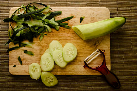 Concept of a healthy vegan food. Peeling and cutting a cucumber