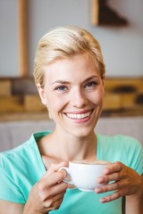 Pretty blonde looking at camera and holding cup of coffee 
