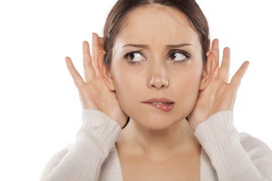 young woman carefully listening  with her hands behind the ears