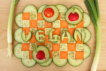 Schachbrettmuster mit Gurke und Karotte mit Schriftzug vegan, verziert mit Dekogemüse