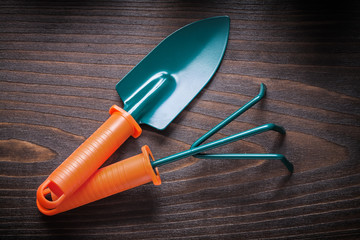 Hand gardening shovel with rake on vintage wooden board agricult