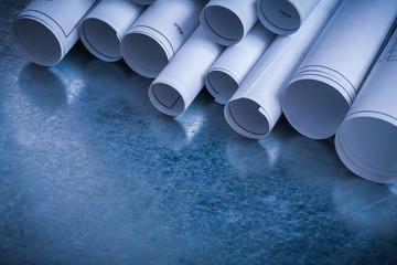 Fototapeta premium Rolls of white construction plans on scratched metallic backgrou