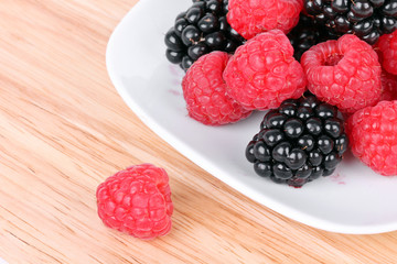 Blackberry and raspberries on white plate