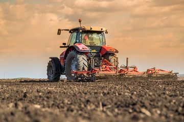 Obraz premium Farmer in tractor preparing land with seedbed cultivator