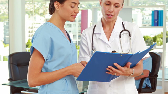Two doctors looking at clipboard in medical office