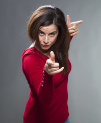 focused brunette woman staring at someone with index finger and torso forward accusing and...