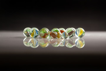Biglie di vetro colorato su piano riflettente con sfondo nero