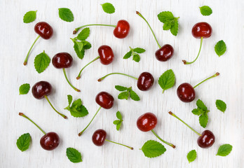 cherries and mint on a white wooden background. top view.