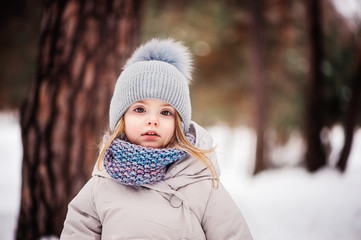 portrait of cute baby girl on winter walk in snowy forest