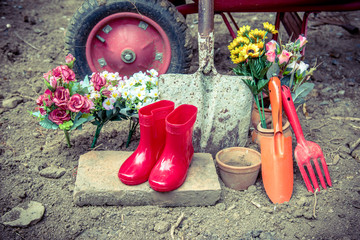 gardening tool including by red boots vase , fork , shovel and barrow , vintage color tone effect