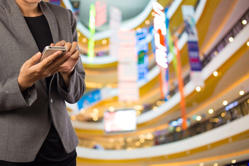 Women in shopping mall using mobile phone.
