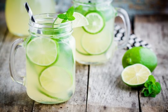 homemade lemonade with lime, mint in a mason jar on a wooden table