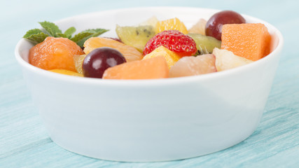 Fruit Salad - Bowl of fresh fruit salad on a blue background.