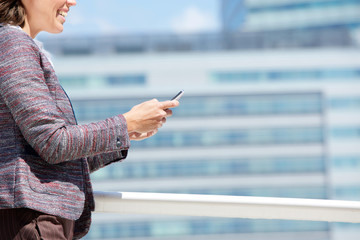 Fototapeta premium Smiling business woman walking and using mobile phone