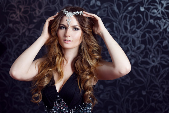 beautiful girl  with long brown curled hair, dark background
