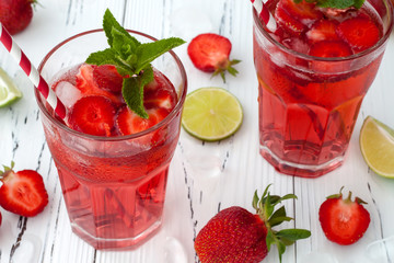 Refreshing summer drink with Strawberry, lime and mint in glasses on white wooden background