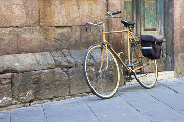 Fototapeta na wymiar Yellow bicycle with bag against a stone wall