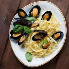 Above view of tagliatelle with boiled mussels and green basil