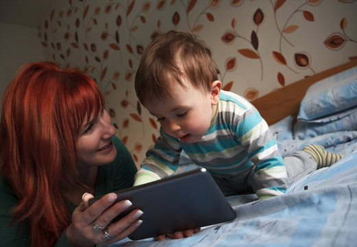 Mother reading bedtime stories to her son on digital tablet