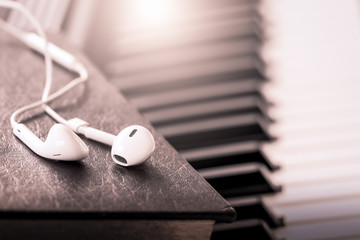 earphone on book on piano key in vintage color tone,music concep