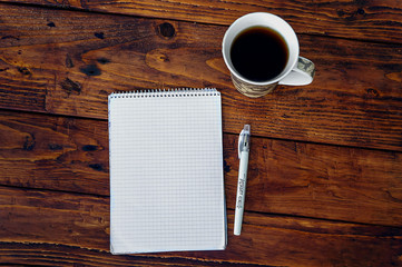 one cup of coffee and notebook on wooden background
