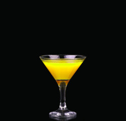 Yellow cocktail in martini glass isolated on black background