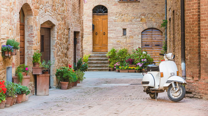 Włoskia uliczka w małym toskańskim miasteczku i popularny skuter